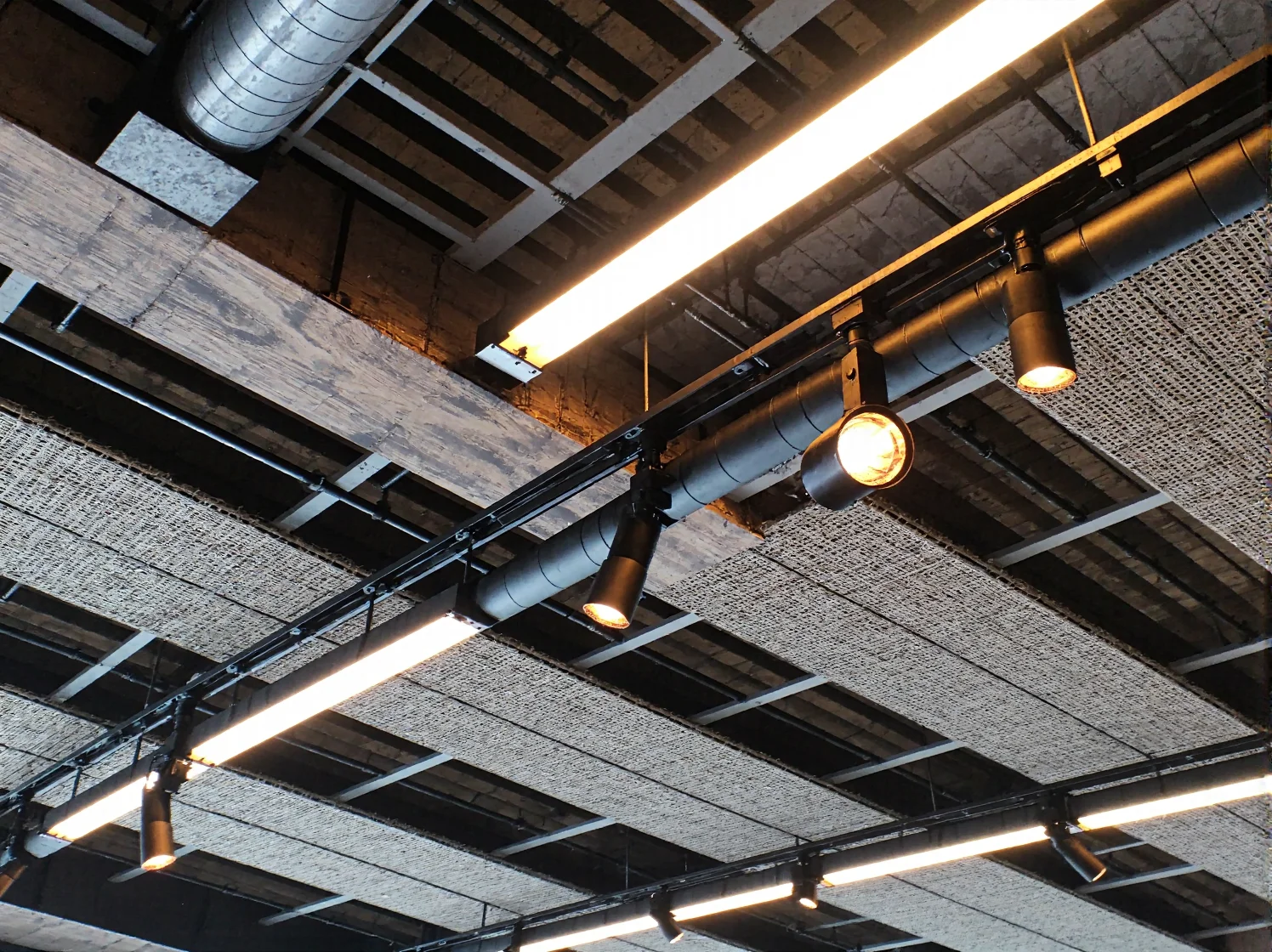 Ciepła barwa światła LED podkreślająca betonowe ściany w sypialni loft